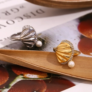Detail of gold and silver scallop shell rings with pearl and crystal inlays on wood