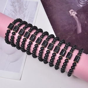Matte black agate zodiac bracelets with gold accents on creative display stands