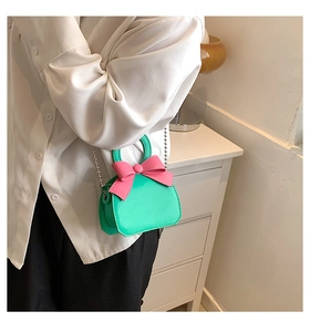Crossbody mini bag in bright green with pink bow detail shown on a model