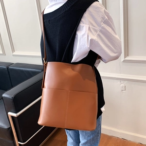 Braune Leder-Eimertasche mit großer Kapazität, am Modell in minimalistischem Raum