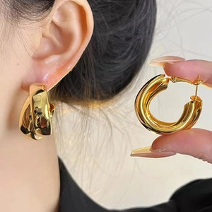 Detail of chunky gold-colored twisted hoop earrings showing texture and closure mechanism