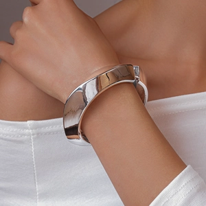 Close-up of a wide polished silver cuff bracelet worn on wrist for a minimalist luxury look