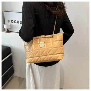 Detail of khaki quilted PU leather shoulder bag with golden chain strap on a model
