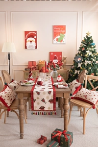 Festive Christmas table runner with reindeer pattern and tassels in a cozy holiday setting