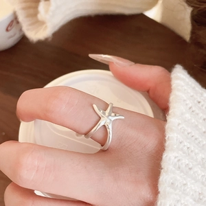 Close-up of a silver starfish-shaped adjustable open ring worn on a finger