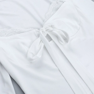 Detailed close-up of white lace trim and bow tie design on long sleeve top