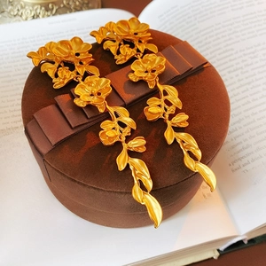 Detail of vintage gold flower and leaf tassel earrings on a brown gift box and book