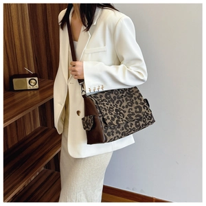 Detail of leopard print tote bag featuring brown leather trim and adjustable shoulder strap