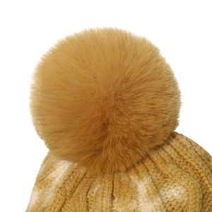 Close-up of ginger yellow knit hat with fluffy faux fur pompom and mixed weave texture