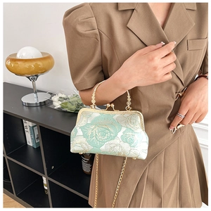 Detail of light green floral embroidery on vintage handbag with metal kiss lock clasp