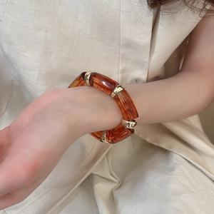 Detail of amber acetate resin links and gold metal rings on a minimalist bracelet