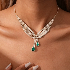 Detail of luxury teardrop emerald pendant necklace with white diamonds on female model neck