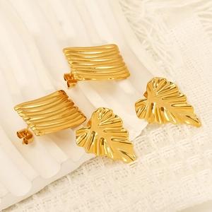 Detailed view of golden stainless steel curved leaf and square textured stud earrings