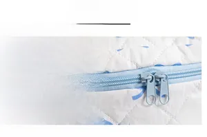 Detail of smooth blue dual zippers on quilted white cosmetic bag with bow prints