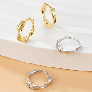 Macro detail of twisted Mobius earrings in gold and silver sterling silver finishes