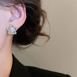 Detail von hohlgeformtem Blumenohrring mit Perle und Zirkon-Inlay am Ohr getragen
