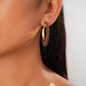 Close-up of leopard print hoop earrings with golden inner finish on a female model