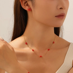 Détail du collier et des boucles d'oreilles dorés avec lèvres en émail rouge sur un mannequin