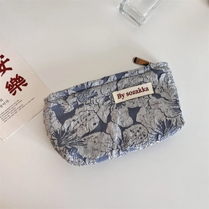 Detailed view of the blue and white floral embossed texture on a fabric makeup bag