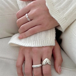 Macro detail of silver ring set with anchor link, heart, and ribbed textures