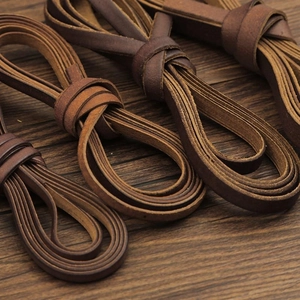 Détails de cordons plats en cuir marron pour bricolage sur fond en bois sombre