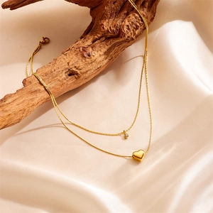 Double-layered golden heart necklace with crystal pendant on silk and wood background