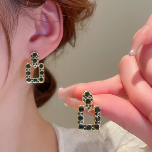 Dettaglio dell'orecchino vintage rettangolare con zircone verde smeraldo e bordo dorato