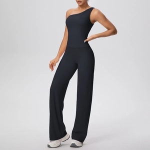 Détail du haut de yoga noir à une épaule et du pantalon large en tissu mat