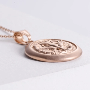 Macro side view of rose gold peace dove pendant necklace with embossed vintage texture