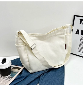 Detail view of a white canvas tote bag with side pockets and a red brand woven label