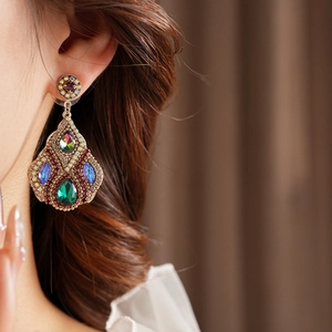 Détail de boucle d'oreille vintage en or avec cristaux émeraude et rubis sur modèle