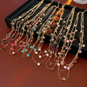 Détail de colliers dorés multicouches avec zircons ronds colorés sur un présentoir noir