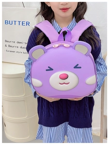 Detail view of a purple cartoon bear hardshell backpack worn by a toddler girl