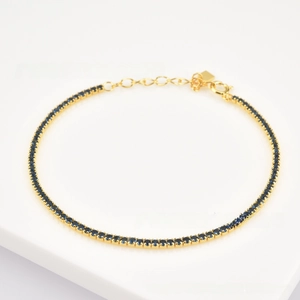 Detail of gold-plated silver chain bracelet with round blue cubic zirconia stones