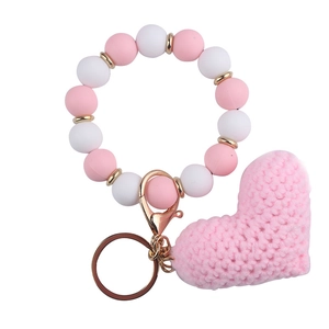 Detailed shot of a pink knitted heart charm and beaded wristband keychain with gold rings