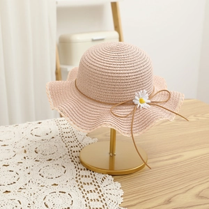 Close-up of pink straw sun hat with wavy lace trim and delicate white daisy detail