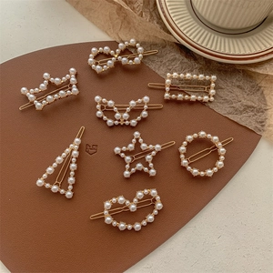 Flat lay of 8-piece gold pearl hair clips in geometric shapes on a vintage brown base