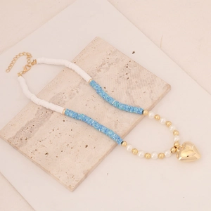 Detailed flat lay of bohemian clay bead necklace with pearl accents and gold heart charm
