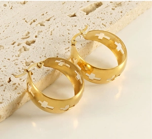 Detail of gold hollow cross pattern on matte stainless steel hoop earrings on stone