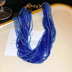 Dettaglio di collana di perline blu multistrato con chiusura OT dorata su vassoio