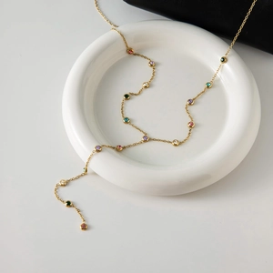 Détail d'un collier en Y plaqué or 18 carats avec strass colorés sur un plateau