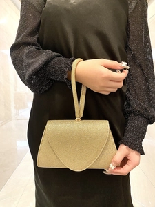 Detail of gold glitter evening clutch bag with triangle flap held by a model