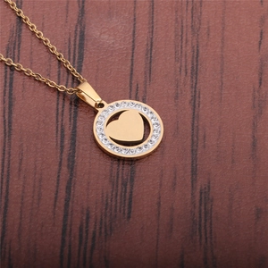 Vista macro di una collana con ciondolo a cuore dorato e zirconi su legno scuro