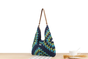 Macro view of textured crochet pattern on a large tricolor woven tote with leather strap