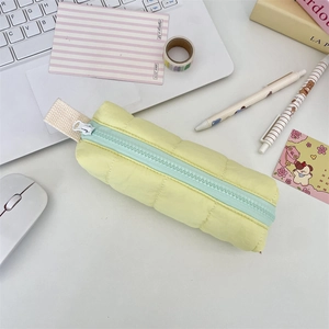 Detail of yellow quilted pencil case with green zipper and soft puff fabric texture