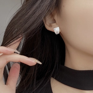 Close-up of minimalist S925 sterling silver ear studs with hammered texture on earlobe