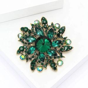 Elegant gold-tone brooch featuring vibrant green crystals and rhinestones for coats