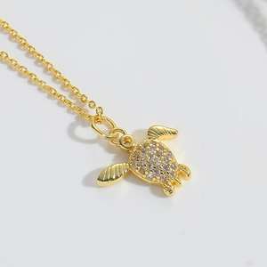 Macro detail of a golden sea turtle pendant necklace featuring sparkling zircon crystals