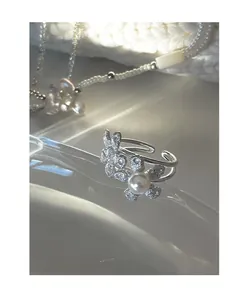 Detail of silver flower ring featuring brushed petals and a white pearl center