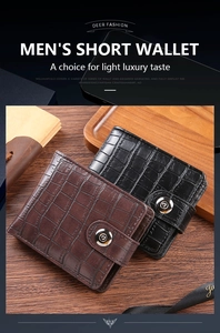 Detail of short men's wallet with crocodile texture and metal buckle on wooden surface